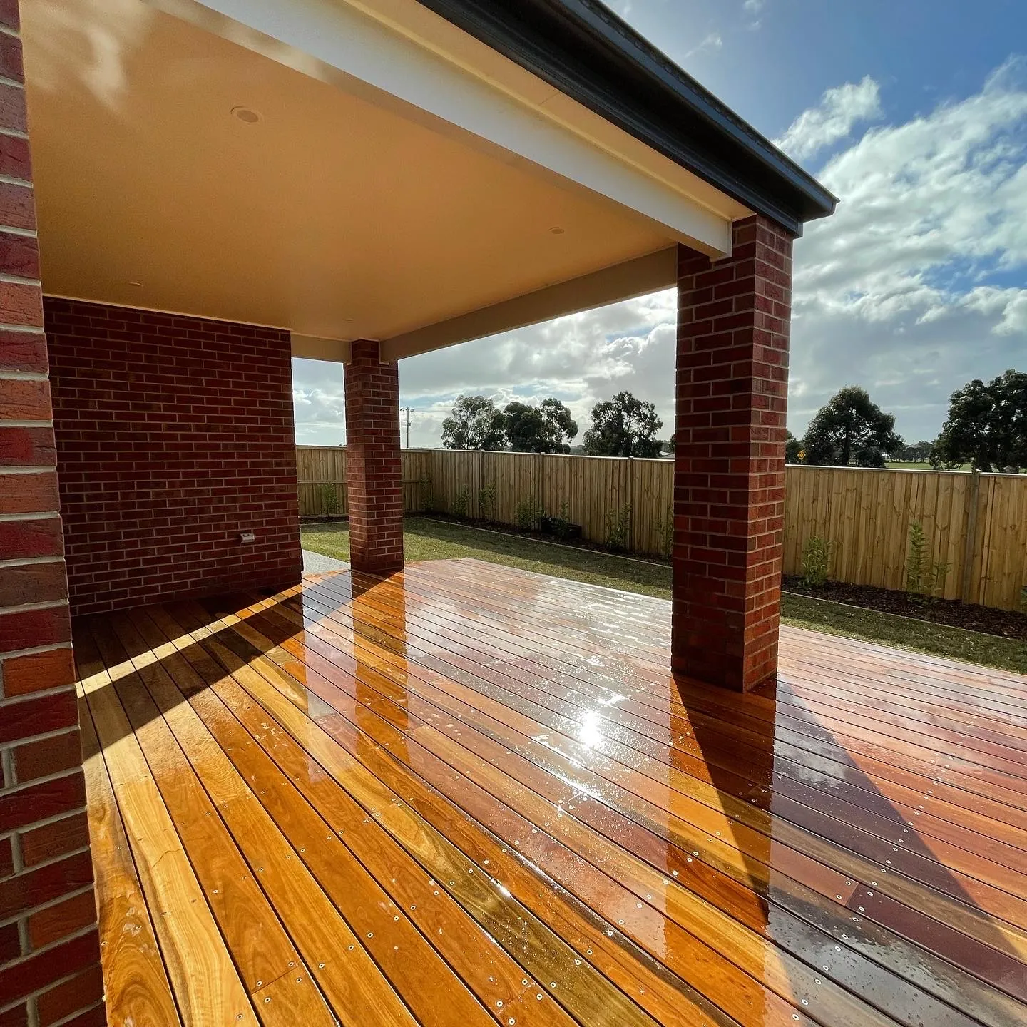 Hardwood deck under a covered alfresco with brick posts